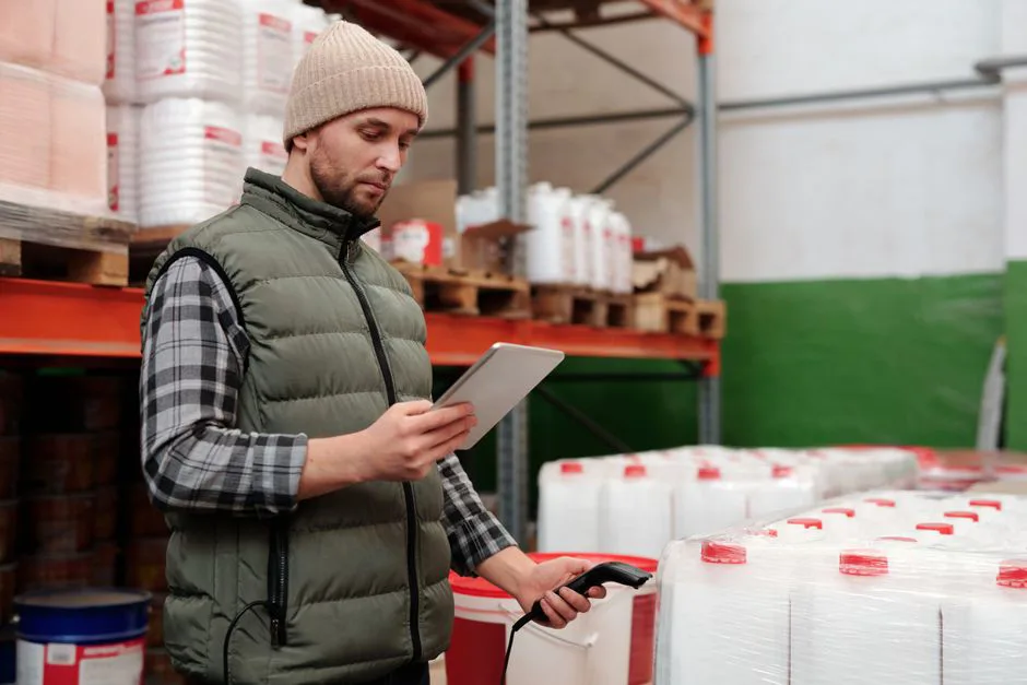 Warehouse worker scanning packages with digital inventory dashboard in background